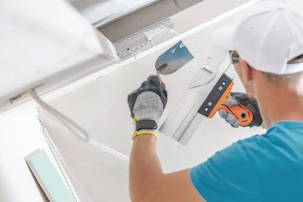 Drywall knife smoothing joint compound over a corner bead